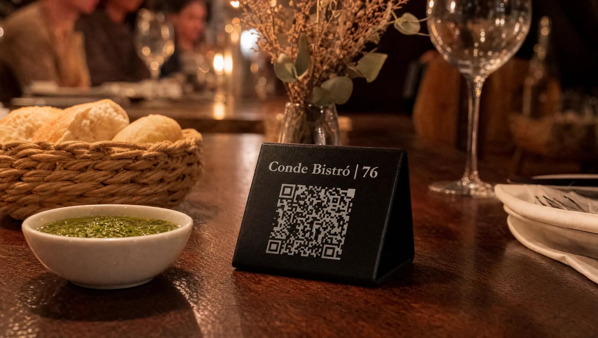 Stand Cartana de noche sobre una mesa puesta con pan amasado, pebre y una copa de vino